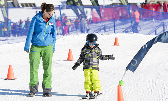 Skilehrerin mit jungem Schüler bei den ersten Versuchen auf Ski