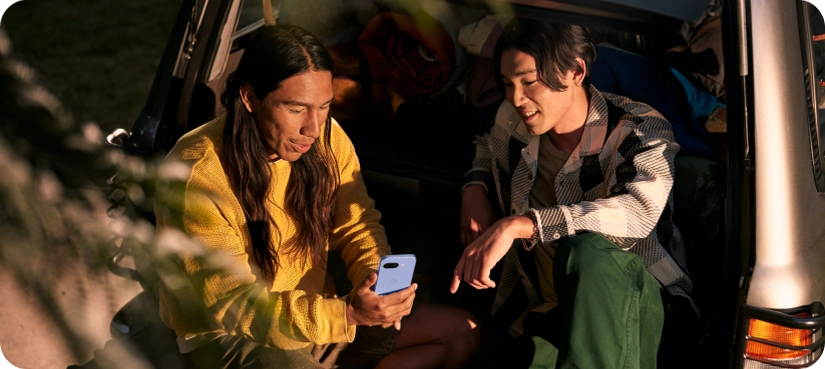 Two friends looking at a Google Pixel 9a
