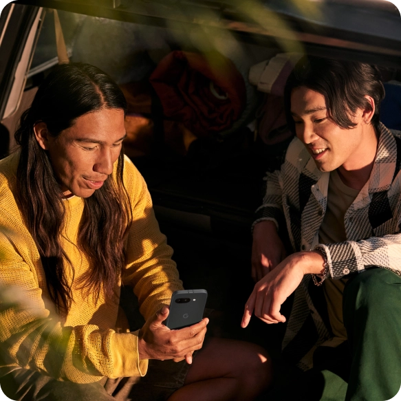 Two friends looking at a Google Pixel 9a