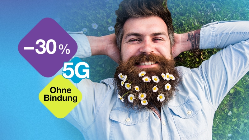 Mann mit Gänseblümchen im Bart liegt auf grünem Rasen